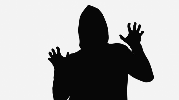 black shadow of maniac in hood showing frightening gesture isolated on white - 写真・画像