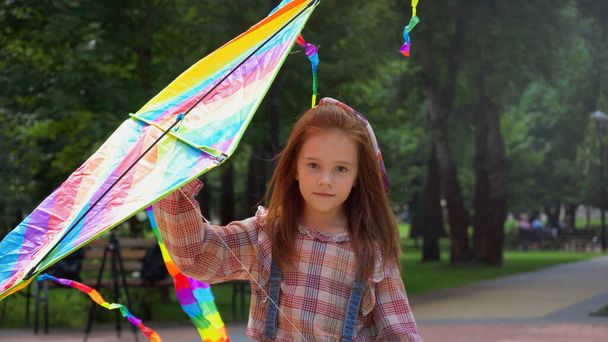 Red haired girl holding flying kite in park - Foto, Bild