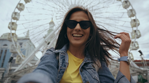 Low angle view of cheerful woman in sunglasses standing on urban street  - Foto, imagen