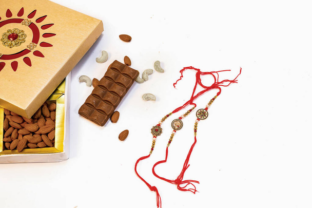 Conceptual rakhi background with chocolate dry fruits rice and flowers for rakshabandhan - Foto, afbeelding