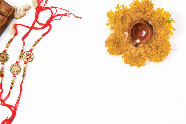 Conceptual rakhi background with chocolate dry fruits rice and flowers for rakshabandhan - Foto, Imagen