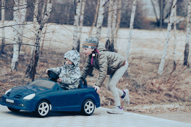 Dos niños felices jugando con un gran coche de juguete viejo en el campo, al aire libre. - Foto, imagen