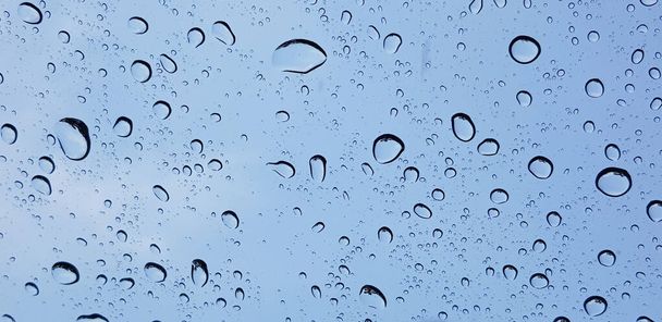 Water droplets perspective through window glass surface against blue sky good for multimedia content backgrounds - Zdjęcie, obraz