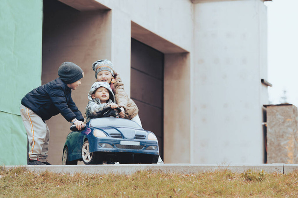 Троє щасливих дітей грають зі старою іграшковою машиною в сільській місцевості, на відкритому повітрі
. - Фото, зображення