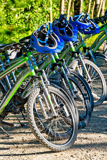 Rental bikes and helmets ready for adventure tour on sunny summer day - Photo, Image