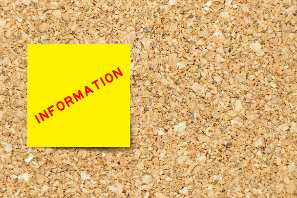 Yellow note paper with word information on cork board background with copy space - 写真・画像