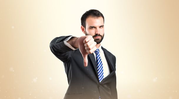 Young businessman with his thumb down over white background  - Photo, Image