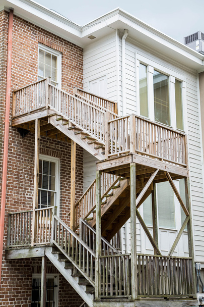 Новые деревянные ступеньки выходят за пределы старых деревянных и кирпичных домов
 - Фото, изображение