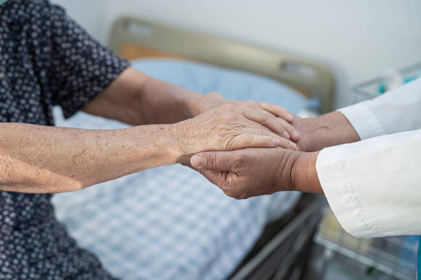 Держать за руки азиатскую пожилую женщину старшего возраста или пожилую женщину пациентку с любовью, уходом, поощрением и сочувствием в стационарном отделении, здоровый сильный медицинский концепт - Фото, изображение