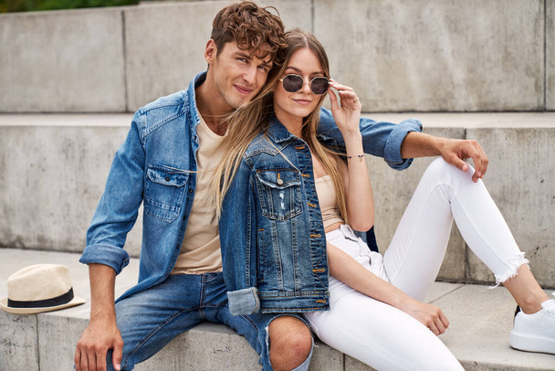 Photo of attractive couple wear denim clothes sitting outdoor and looking at camera - Zdjęcie, obraz