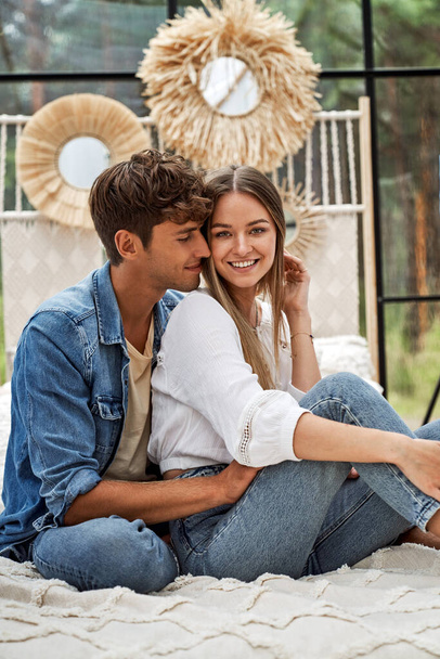 Young cute couple sitting on the bed in boho scenery - Foto, Imagen