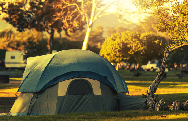Modern Tent in Khaki Green Color with Additional Roof Protector Cover Pitched and Secured on a Campground. Fall Foliage in the Background. Camping and Outdoor Stay Theme. - Photo, Image