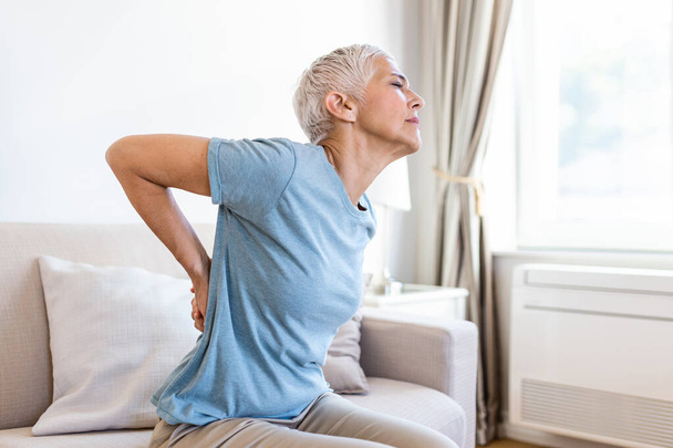 Matur Woman suffering from lower back pain. Mature woman resting with back pain. Female lower back pain. Senior woman injury suffering from backache - Fotoğraf, Görsel