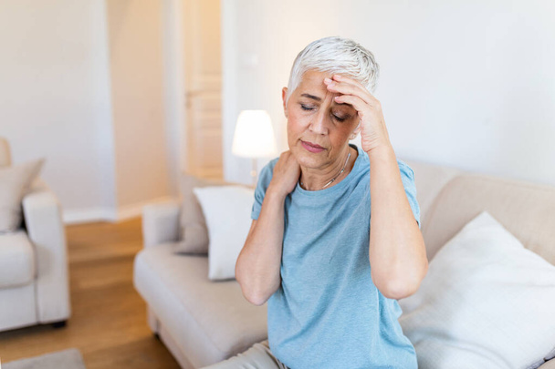 Támadás a szörny migrén. Szinuszfájdalom. A boldogtalan nyugdíjas idős nő fájdalommal fogja a fejét. A fejfájásban szenvedő idős nő arca - Fotó, kép