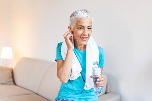 Senior woman with headphones while resting after workout. Athletic mature woman resting after a good workout session - Φωτογραφία, εικόνα