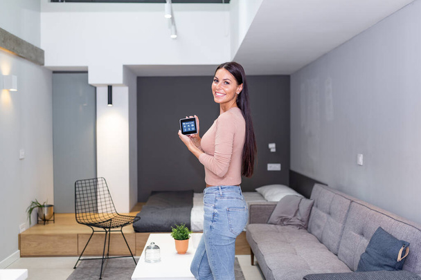 Smart home technology interface on smart controler app screen with augmented reality (AR) view of internet of things (IOT) connected objects in the apartment interior, person holding device - Foto, afbeelding
