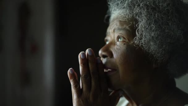 Eine ältere afrikanische Frau, die zu Gott betet und mit Hoffnung und Glauben die Augen schließt - Filmmaterial, Video