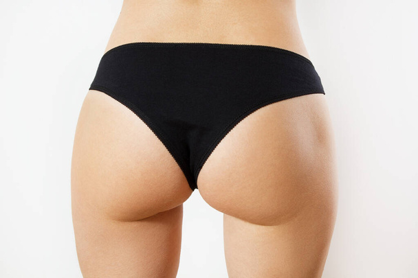 Perfect female sexy buttocks isolated - Cropped close up half-turned photo of ideal elastic flawless beautiful woman's ass wearing white underlinen underclothes isolated on background. - Φωτογραφία, εικόνα