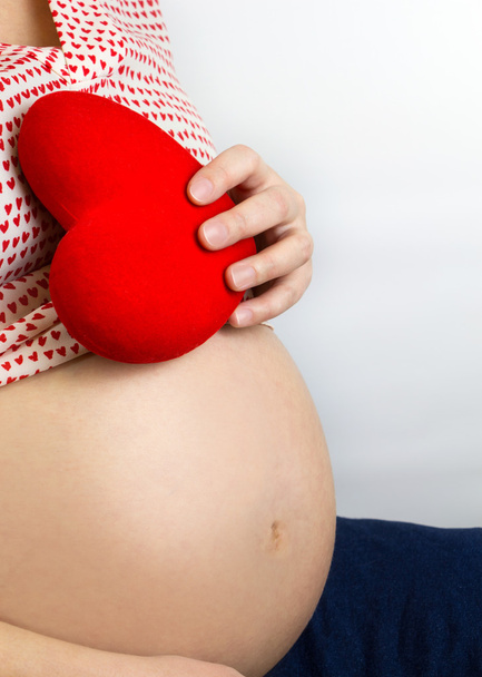 Беременная женщина с красным сердцем на животе
 - Фото, изображение