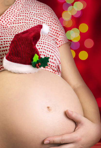 Kobieta w ciąży ładny brzuch z Mikołaje kapelusz i bokeh tło - Zdjęcie, obraz