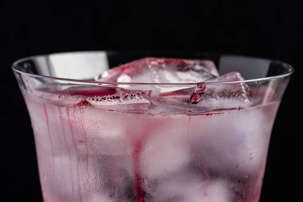 Detailní záběr osvěžujícího nápoje s kostkami ledu v rosném skle na černém pozadí.Výborný obraz pro osvěžující koktejlové transparenty a reklamy. Místo pro textovku. hedonický životní styl - Fotografie, Obrázek