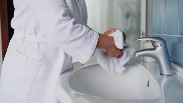 Close-up. Woman in bathrobe, washing hands with a liquid antibacterial soap, wiping with a terry towel and applying moisturiser. Hygiene, sanitary, cleanliness. White washbasin and stainless faucet - Video