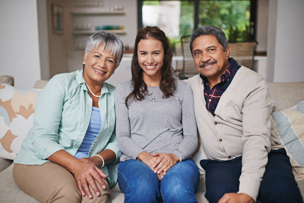 This one is for the family album. Family portrait of a young woman and her mature parents sitting on a sofa in the living room - Foto, afbeelding