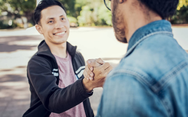 Two teenage friends shaking hands at each other outdoors. Two people shaking hands on the street. Concept of two friends greeting each other with handshake on the street - Foto, imagen