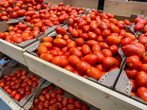 Fresh organic red pear tomatoes in a market or supermarket. Tomatoes in boxes in a food store - Фото, изображение