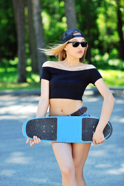 Красива і модна молода жінка позує зі скейтбордом
 - Фото, зображення