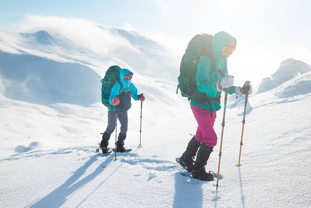 Dwie kobiety chodzą w śnieżnych butach, zimą trekking, dwie osoby w górach zimą, sprzęt turystyczny - Zdjęcie, obraz