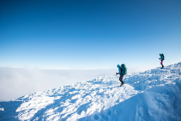 Две женщины в рюкзаках ходят в снегоступах по снегу, зимние походы, два человека в горах зимой, туристическое снаряжение - Фото, изображение