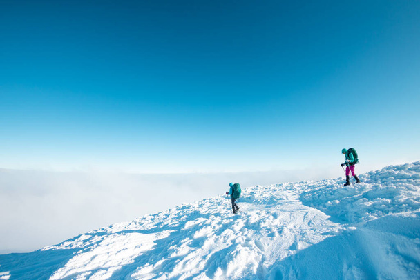 two girls walk along a mountain path in snowshoes. walking in the snow. hiking in the mountains in winter. - 写真・画像