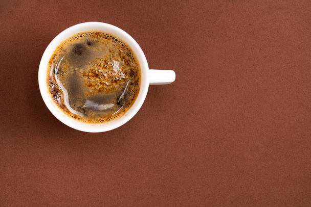 Café espumoso em uma xícara de porcelana no fundo marrom - Foto, Imagem