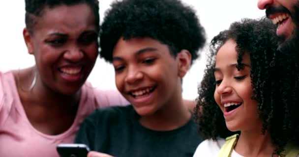 Szczęśliwa rodzina śmieje się razem patrząc na komórkę w domu - Materiał filmowy, wideo