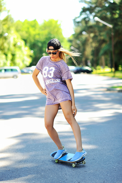 Young woman down the road with a skateboard - Photo, Image