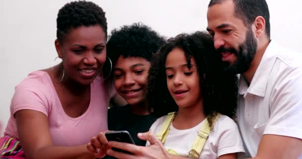 Interracial family using cellphone. Mixed race parents and children looking at smartphone device - Video