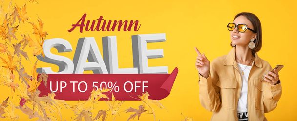 Pretty young woman with phone on yellow background. Banner for autumn sale - Zdjęcie, obraz