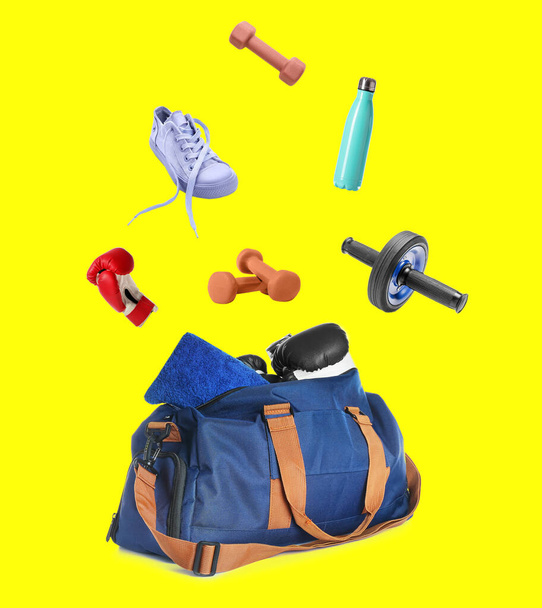 Sports bag and different equipment on yellow background - Foto, imagen