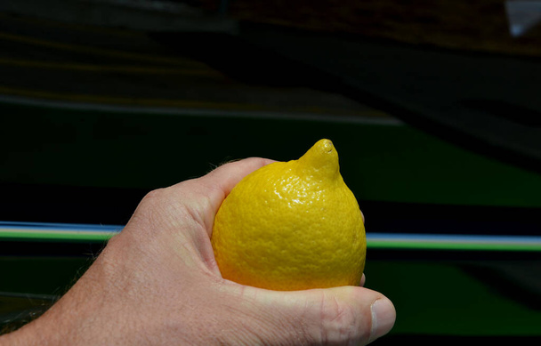 the breast in the hand represents yellow lemon. a man's hand crushes lemon, which in imagination is a woman's, girl's breast. green background. vitamins and for young people, increases sexual libido - Photo, image