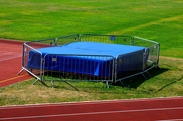 an obstacle course for athletes, a high jump into a mattress in the school yard. a running oval with marked lanes with numbers for five runners - Fotó, kép