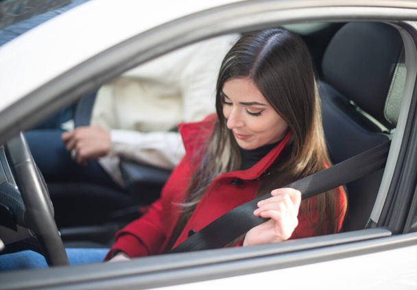 Young woman fastening safety belt in her car - Photo, Image