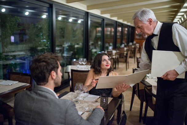 Young couple ordering dinner in a luxury restaurant - Фото, изображение