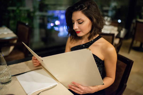 Young woman looking at a menu in the restaurant - Fotó, kép