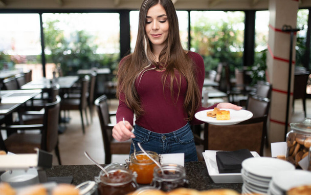 Young woman having a sweet breakfast in a hotel restaurant - Фото, зображення
