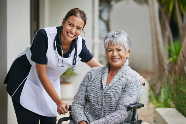 Shes the nurse I want to be by my side. Portrait of a senior woman in a wheelchair being for for by a nurse at a retirement home - Foto, Imagem