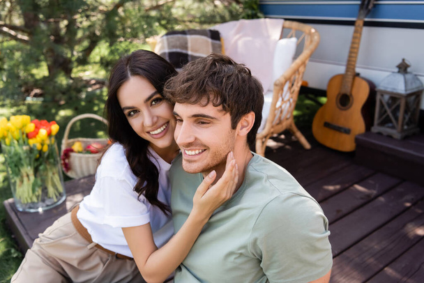 Young woman touching brunette boyfriend near blurred camper van  - Foto, immagini