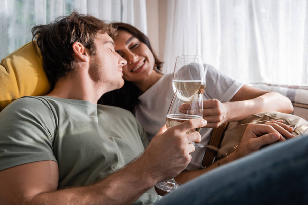 Positive couple holding wine and resting on bed in camper van - Foto, immagini