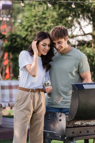 Positive couple with wine cooking on grill outdoors  - Fotoğraf, Görsel