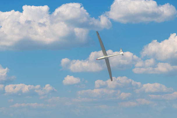 A light glider plane flies in the blue sky with white clouds. - Photo, Image